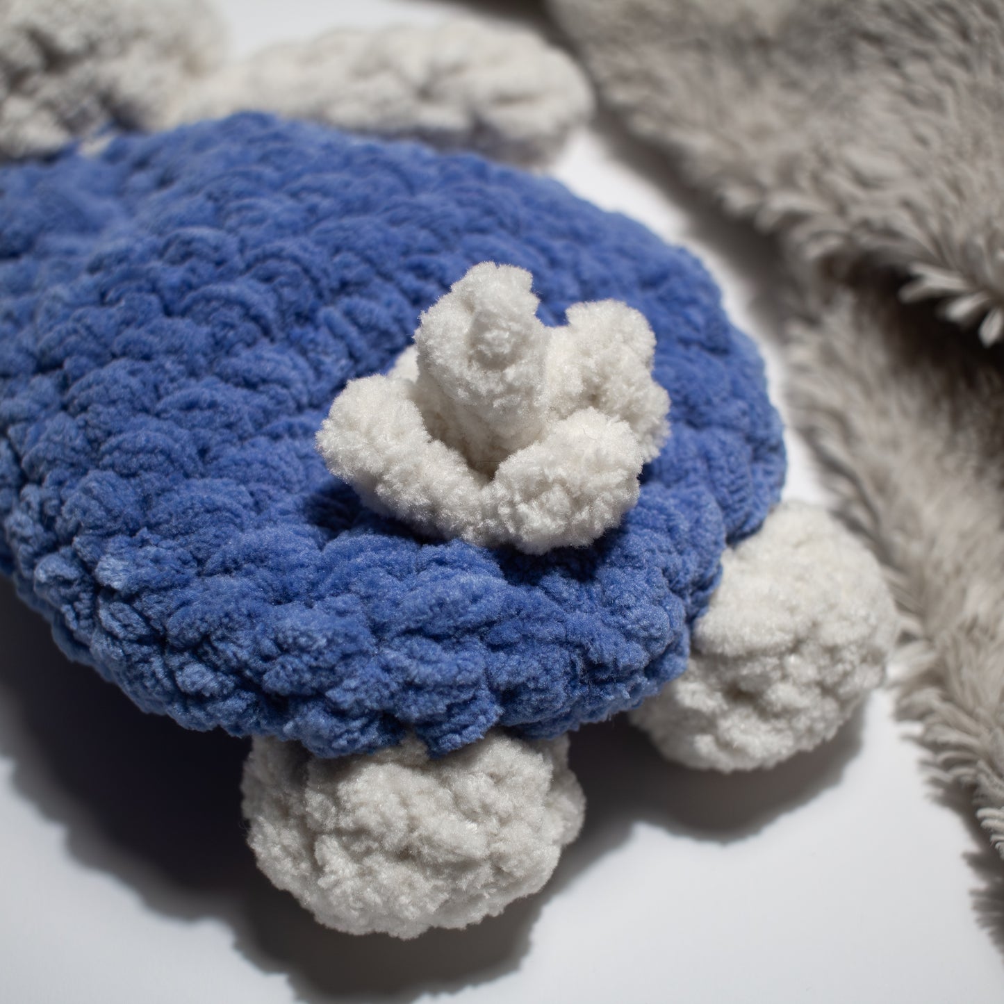 Sininen käsintehty söpö unipupu vauvalle, jolla töpö häntä takana.