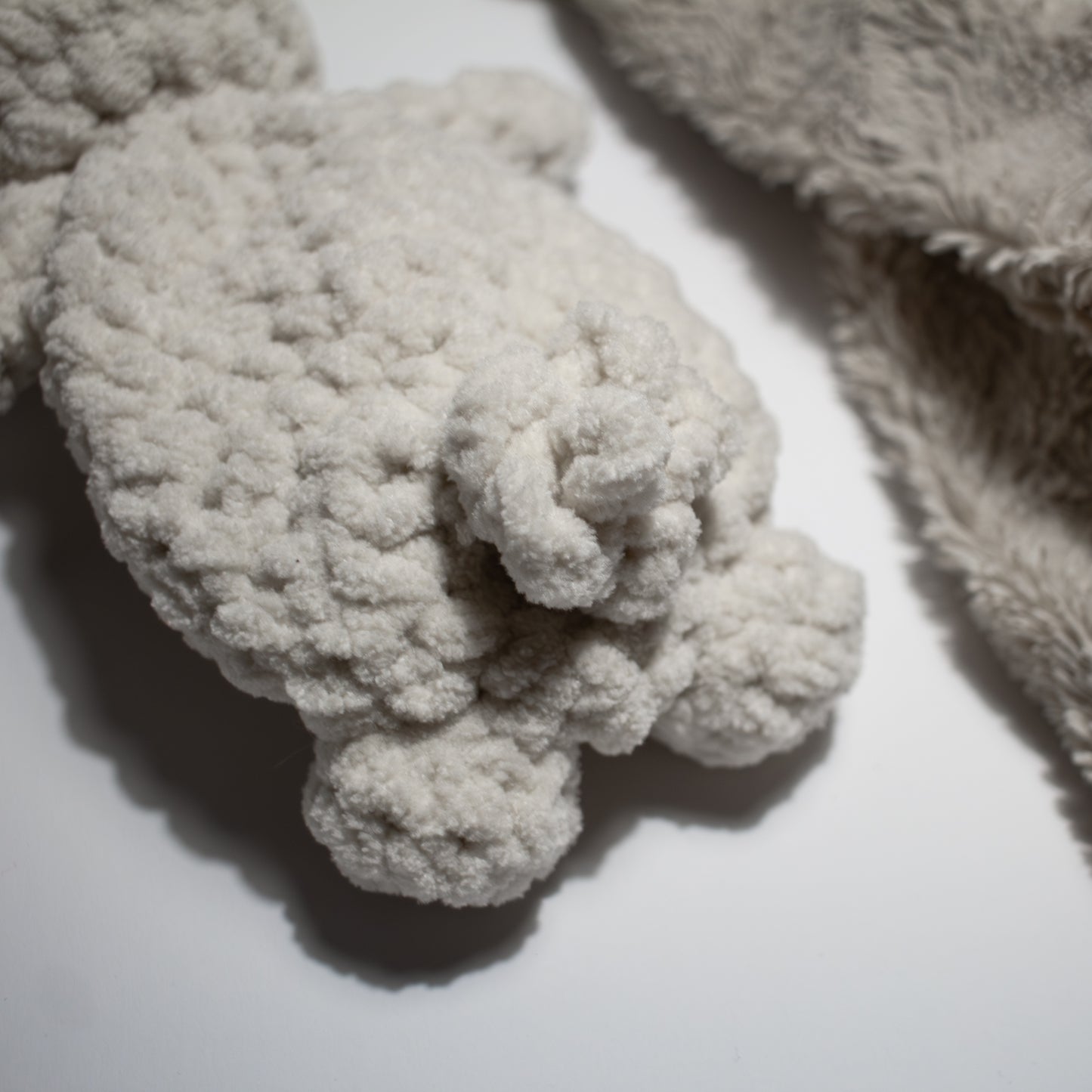 Valkoinen käsintehty söpö unipupu vauvalle, jolla ihana töpö häntä takana.