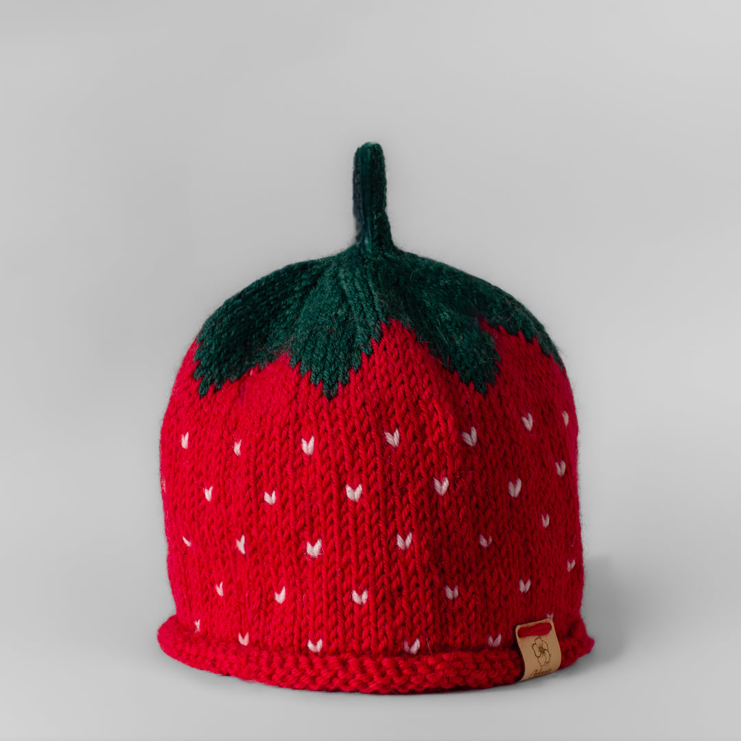 Lasten punainen neulottu käsintehty mansikka pipo, jossa valkoisia pilkkuja ja vihreä lehtiosa jossa vihreä retro antenni.