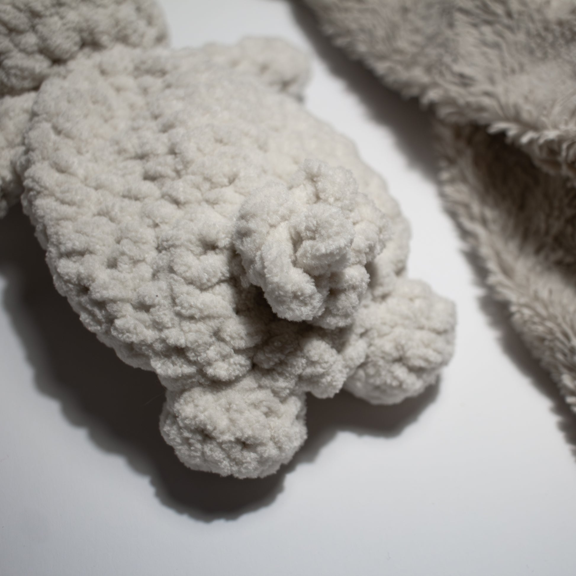 Valkoinen käsintehty söpö unipupu vauvalle, jolla ihana töpö häntä takana.