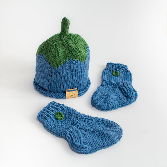 Sininen käsintehty neulottu mustikkapipo, jossa vihreä lehtiosuus sekä kaksi pientä vauvan sinistä mustikka villasukkaa, jossa pienet lehdet.